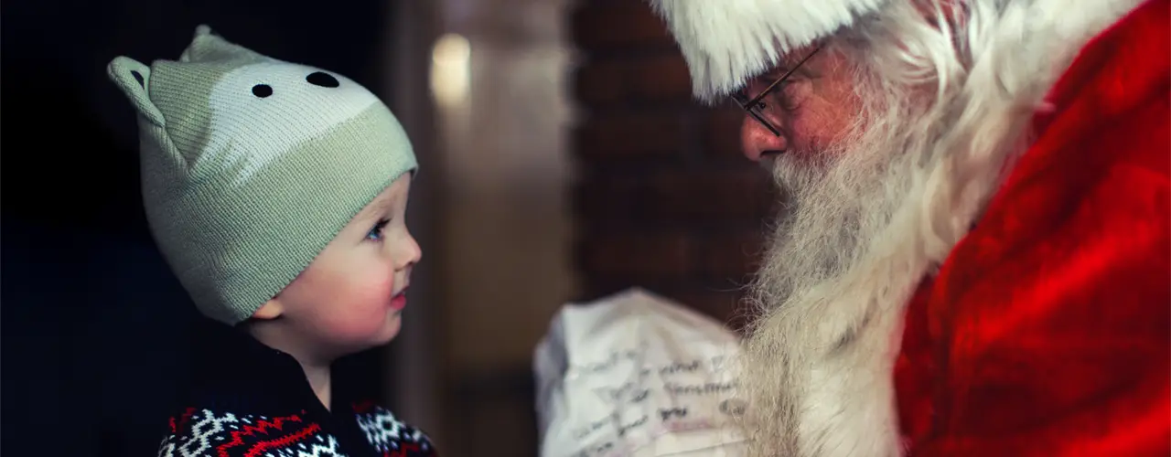 Kleinkind und Weihnachtsmann bei der Geschenke-Übergabe