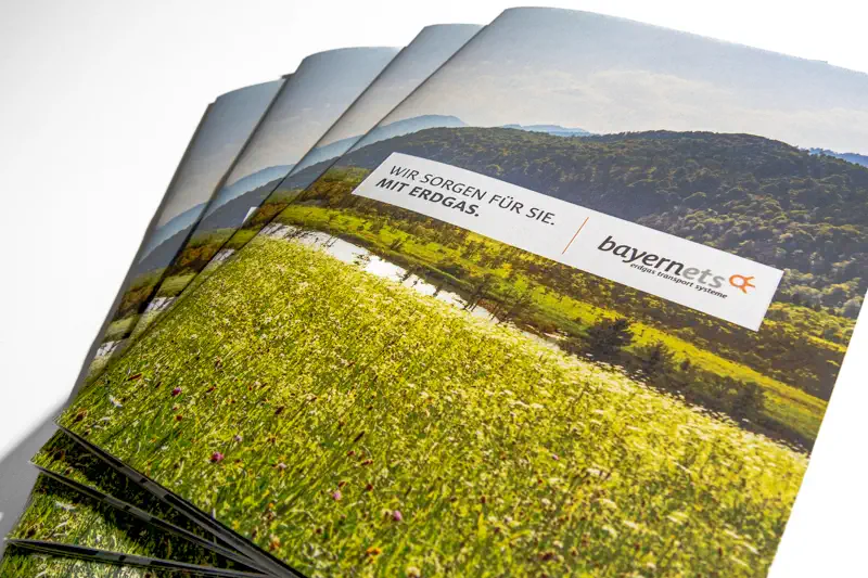 Titelseite einer Imagebroschüre. Bayernets Logo vor grünem Landschaftsbild mit Wiese und Bergen im Hintergrund.