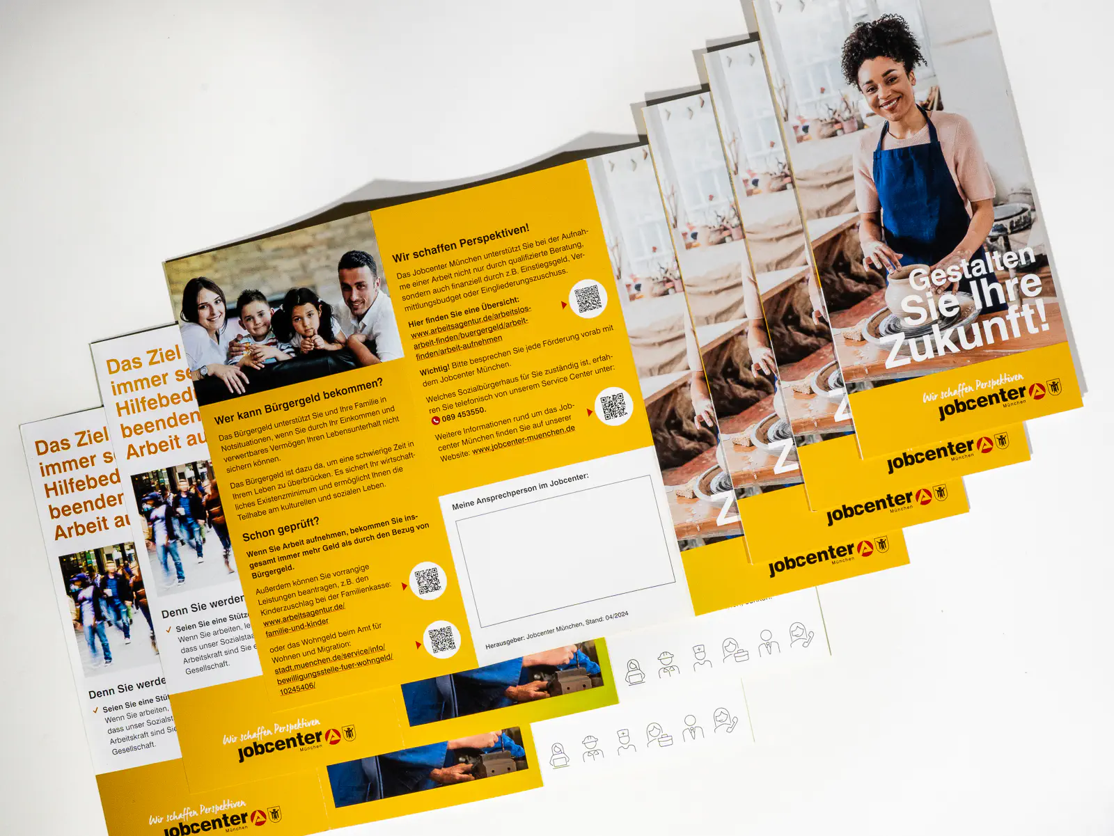 Mehrere gefächerte Flyer des Jobcenters mit dem Titel „Gestalten Sie Ihre Zukunft!“. Das Design ist in Gelb und Weiss gehalten, mit schwarzen und roten Akzenten. Auf der Titelseite ist eine lächelnde Frau in einer Schürze beim Töpfern zu sehen. Die Innenseiten enthalten Informationen zum Bürgergeld, Unterstützungsangebote sowie QR-Codes für weiterführende Inhalte. Ein weiteres Bild zeigt eine Familie mit zwei Kindern. Die Broschüren betonen Perspektiven und Hilfestellungen zur Arbeitsmarktintegration.