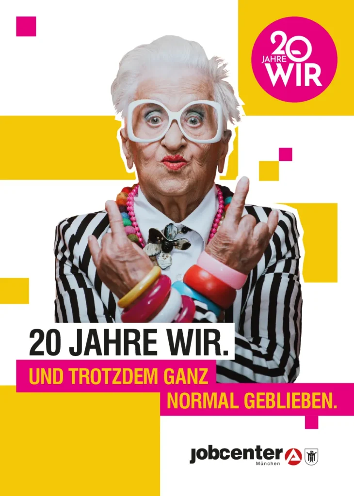 Anniversary poster for Jobcenter München featuring an older woman with white hair, oversized white glasses, a striped jacket and colourful jewellery. Text: “20 Jahre WIR. Und trotzdem ganz normal geblieben.”.
